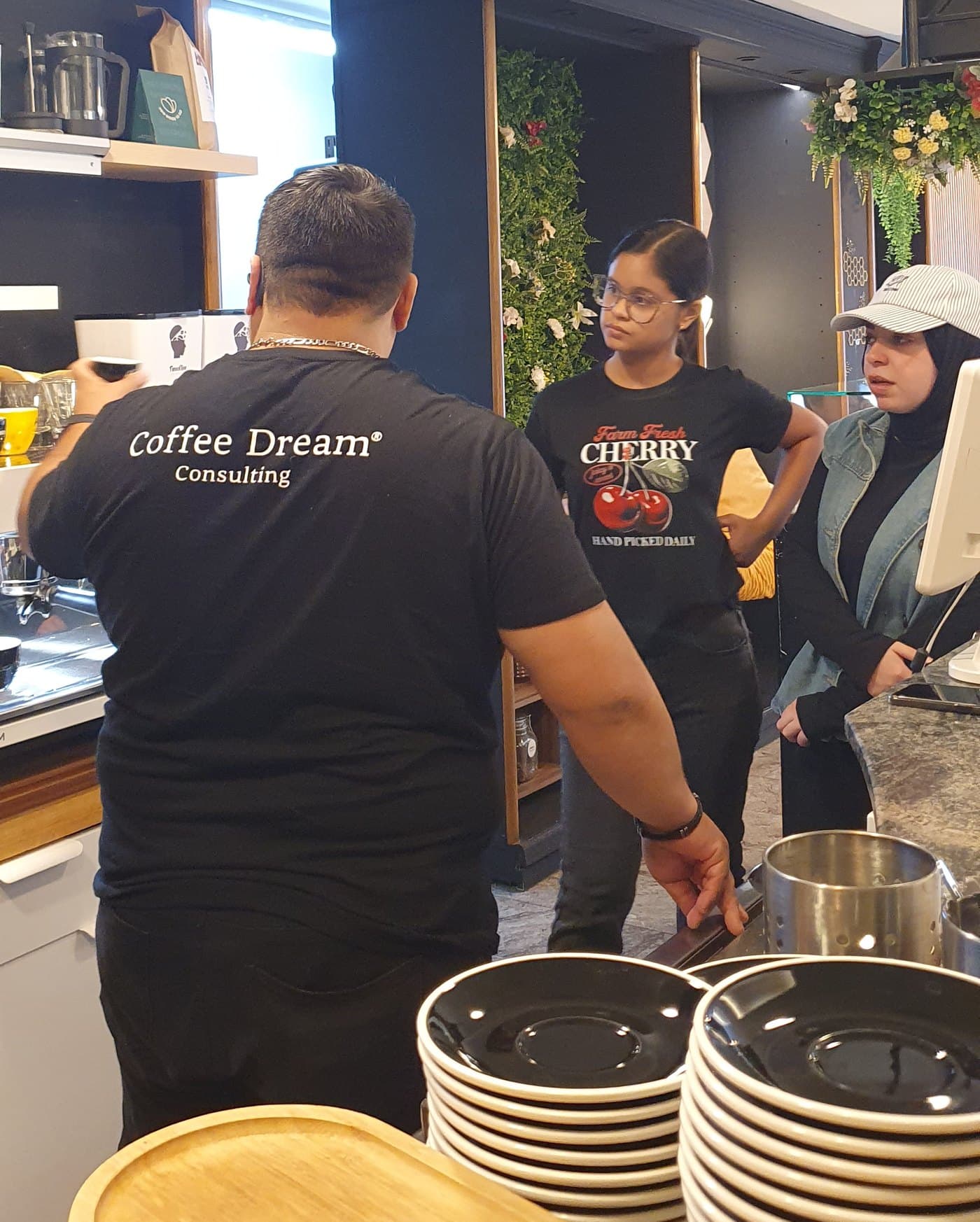 Barista Richy explicando a dos alumnas en la barra